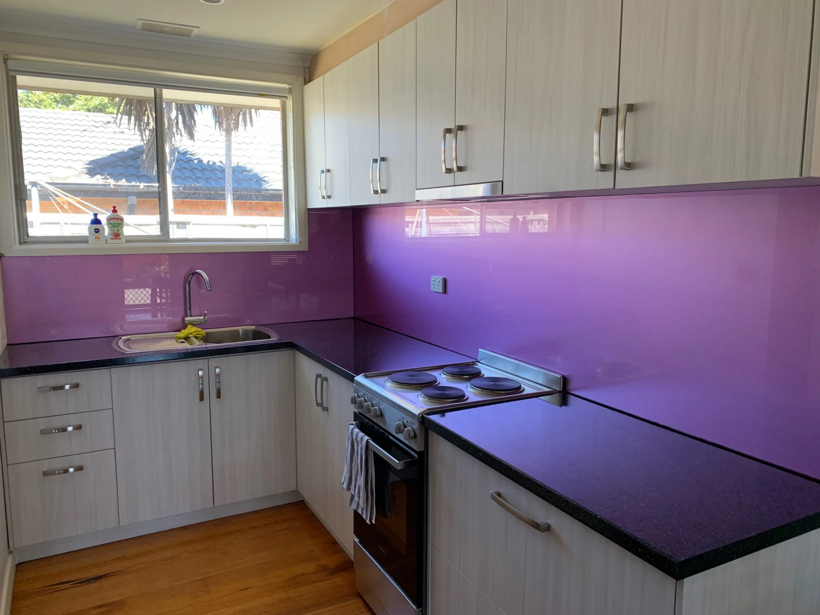 Purple glass splashback wrapping around a white kitchen