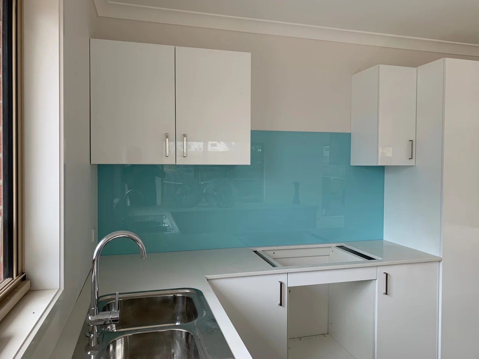 Light blue glass splashback in a compact white kitchen