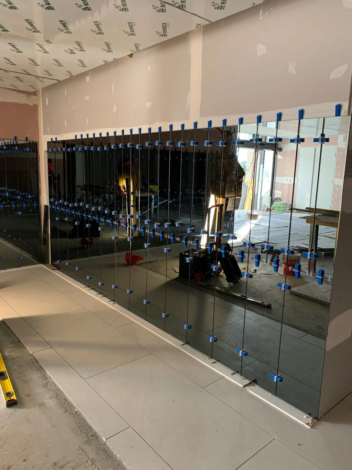 Mirrored wall panels being installed with suction equipment