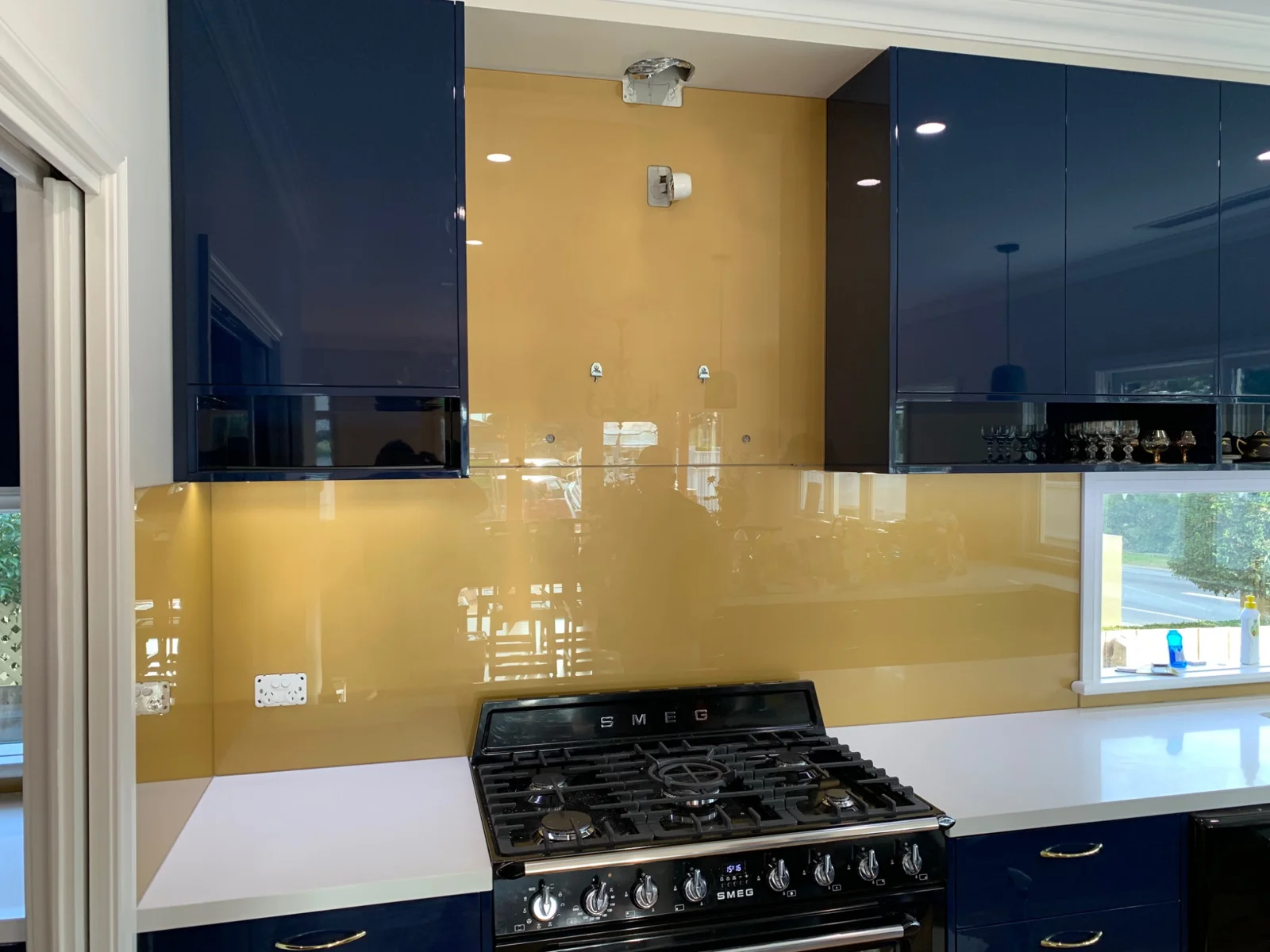 Golden coloured glass splashback with blue kitchen cabinetry