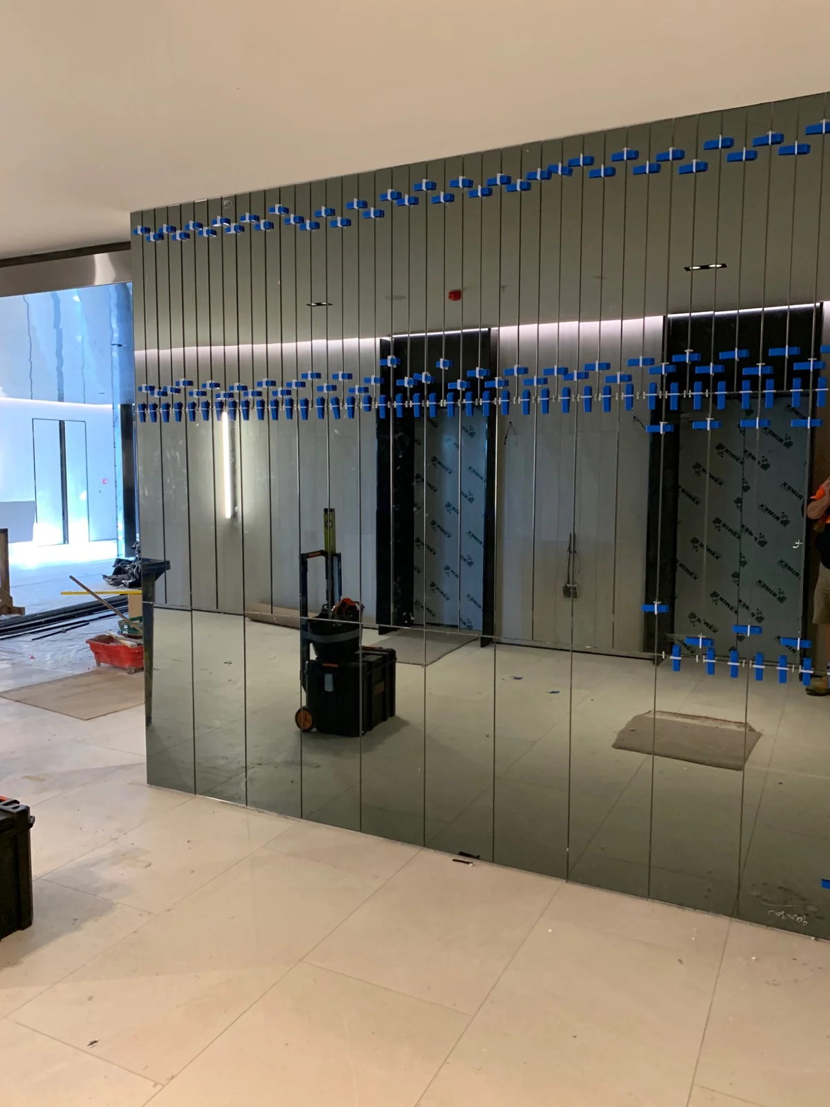 Mirrored wall panels with installation equipment visible
