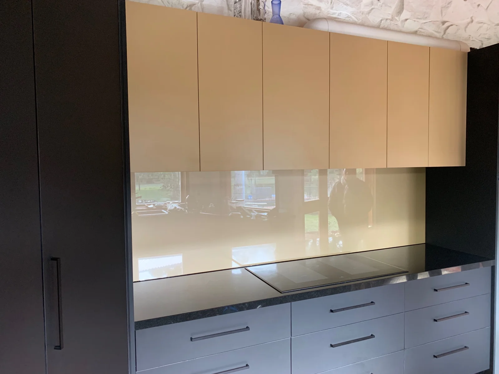 Neutral cream glass splashback under timber-toned kitchen cabinets
