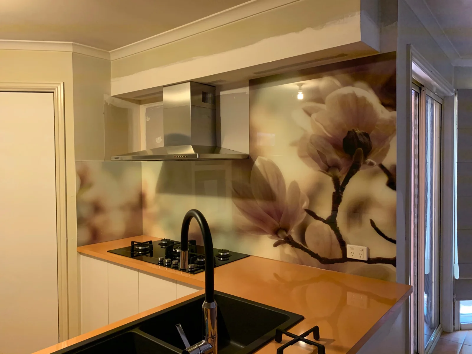 Large flower artwork on a kitchen glass splashback