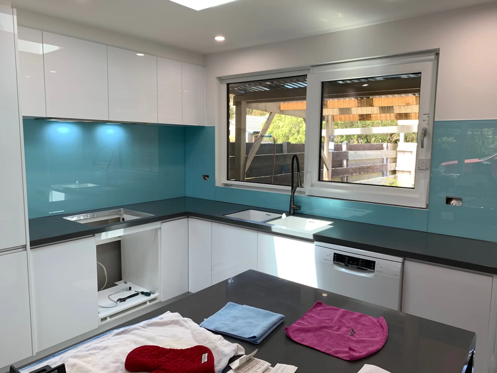 Aqua glass splashback wrapping around a kitchen