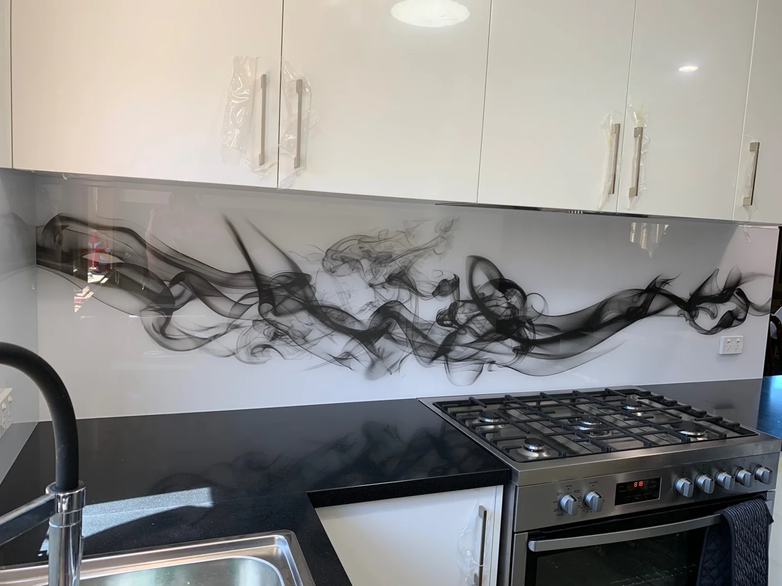 Flowing black abstract artwork on a white glass splashback