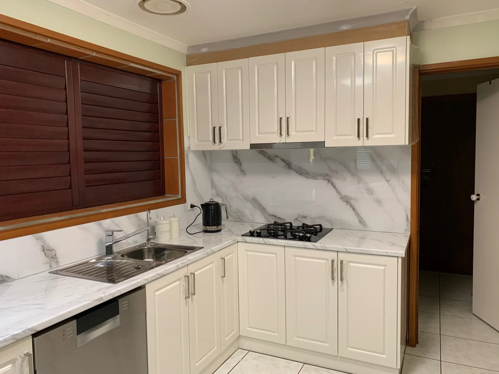 White and grey marble-effect glass splashback in a white kitchen