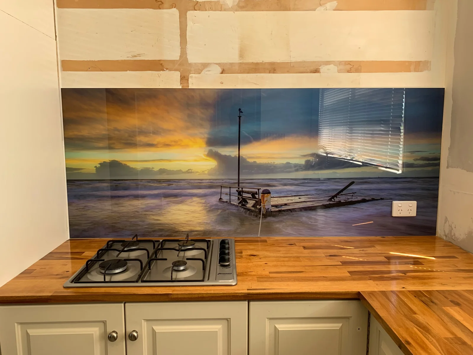 Sailboat and sunset artwork on a glass splashback during installation
