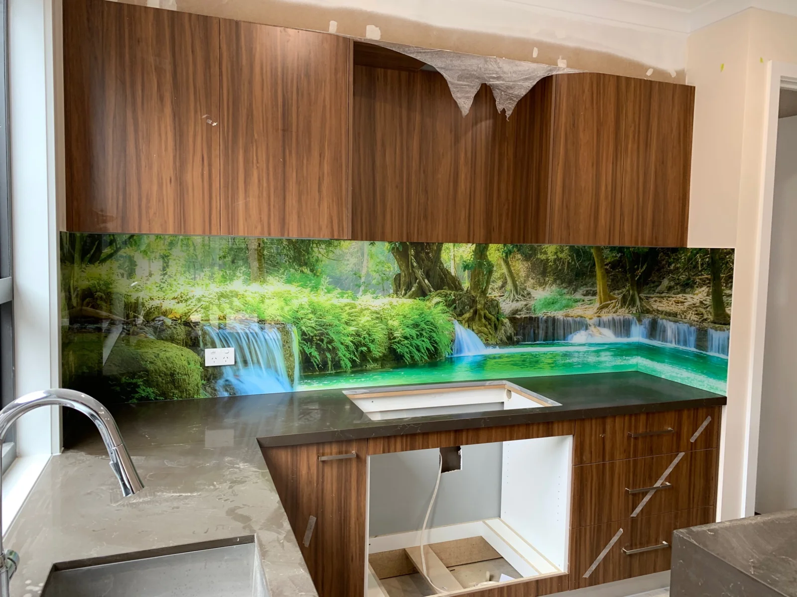 Green waterfall scene printed on glass in a kitchen during installation