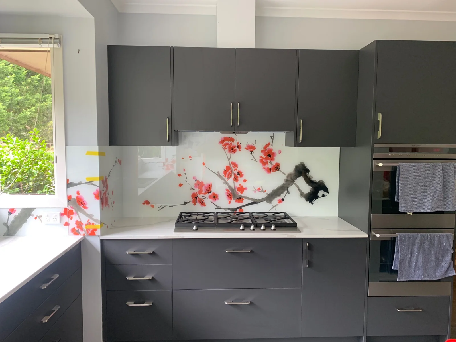 Red and black abstract artwork on a white kitchen splashback