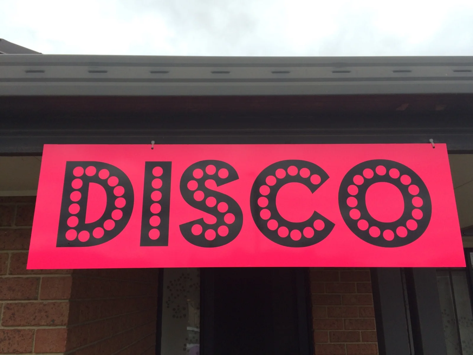 Pink and black disco sign mounted outside