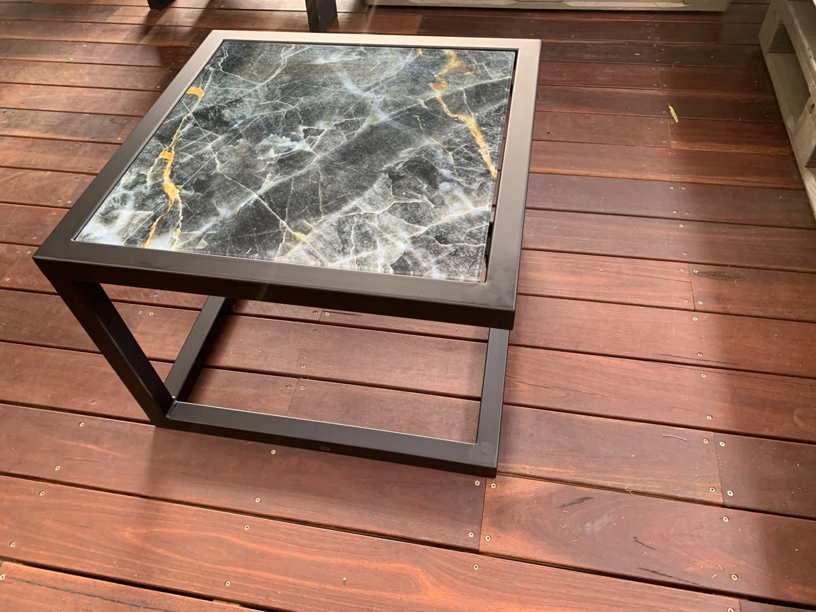 Full view of a steel-base table with charcoal marble-effect printed glass