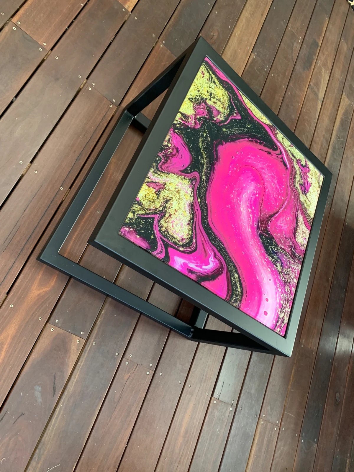 Top view of vivid pink and gold artwork on a glass coffee table
