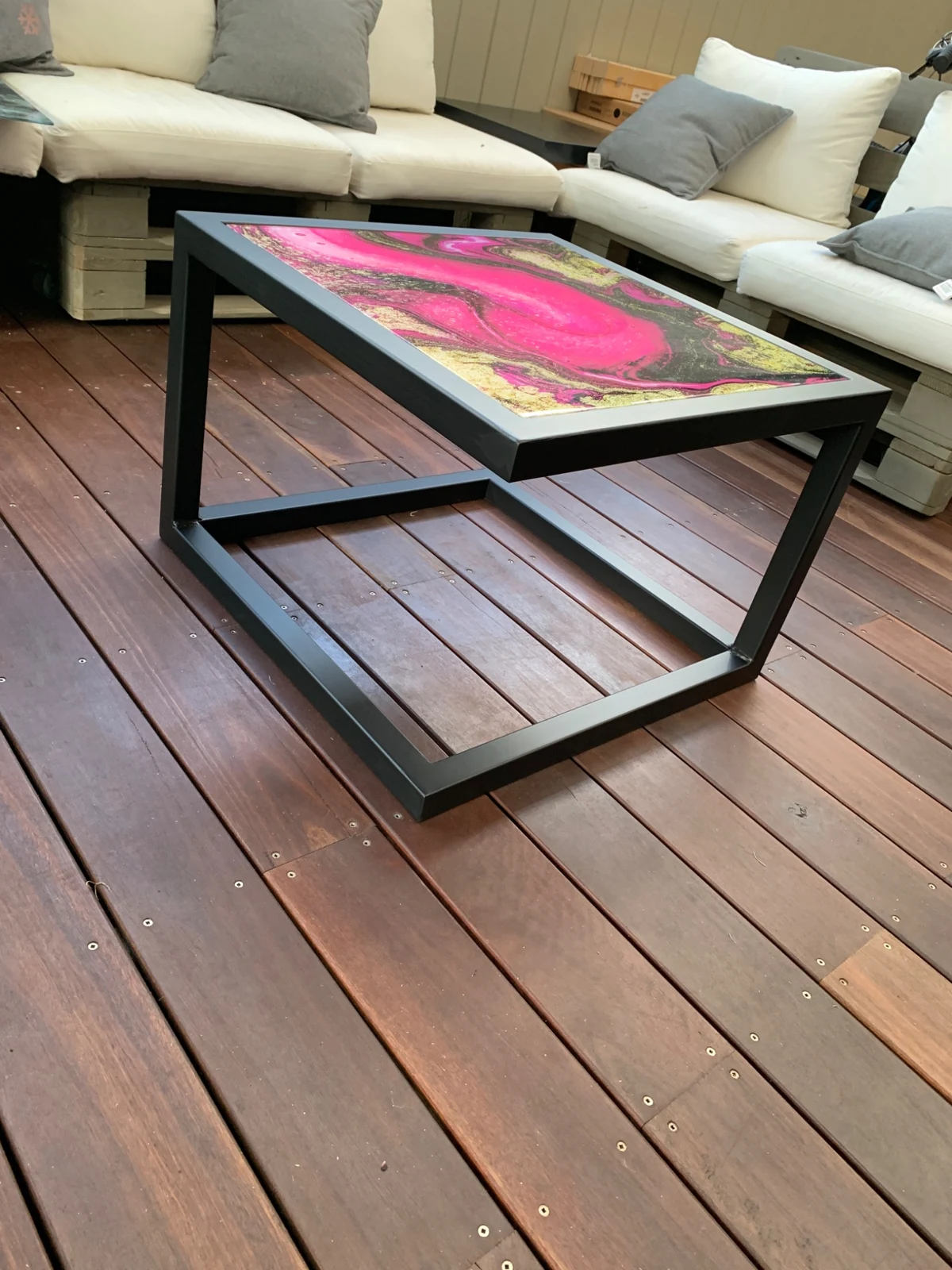 Full view of the pink and gold glass coffee table and black steel base